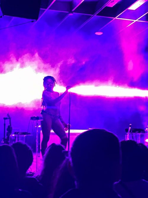 a stage with purple lighting and sillhouette of singer holding mic
